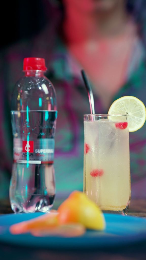 rețete de cocktail tom collins intr-un pahar inalt garnisit cu lamaie si cirese confiate si o sticlă de apa minerala aqua carpatica forte