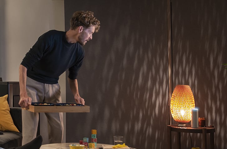 barbat tanar intr-un living amenajat in culori inchise lumina ambientala relaxanta