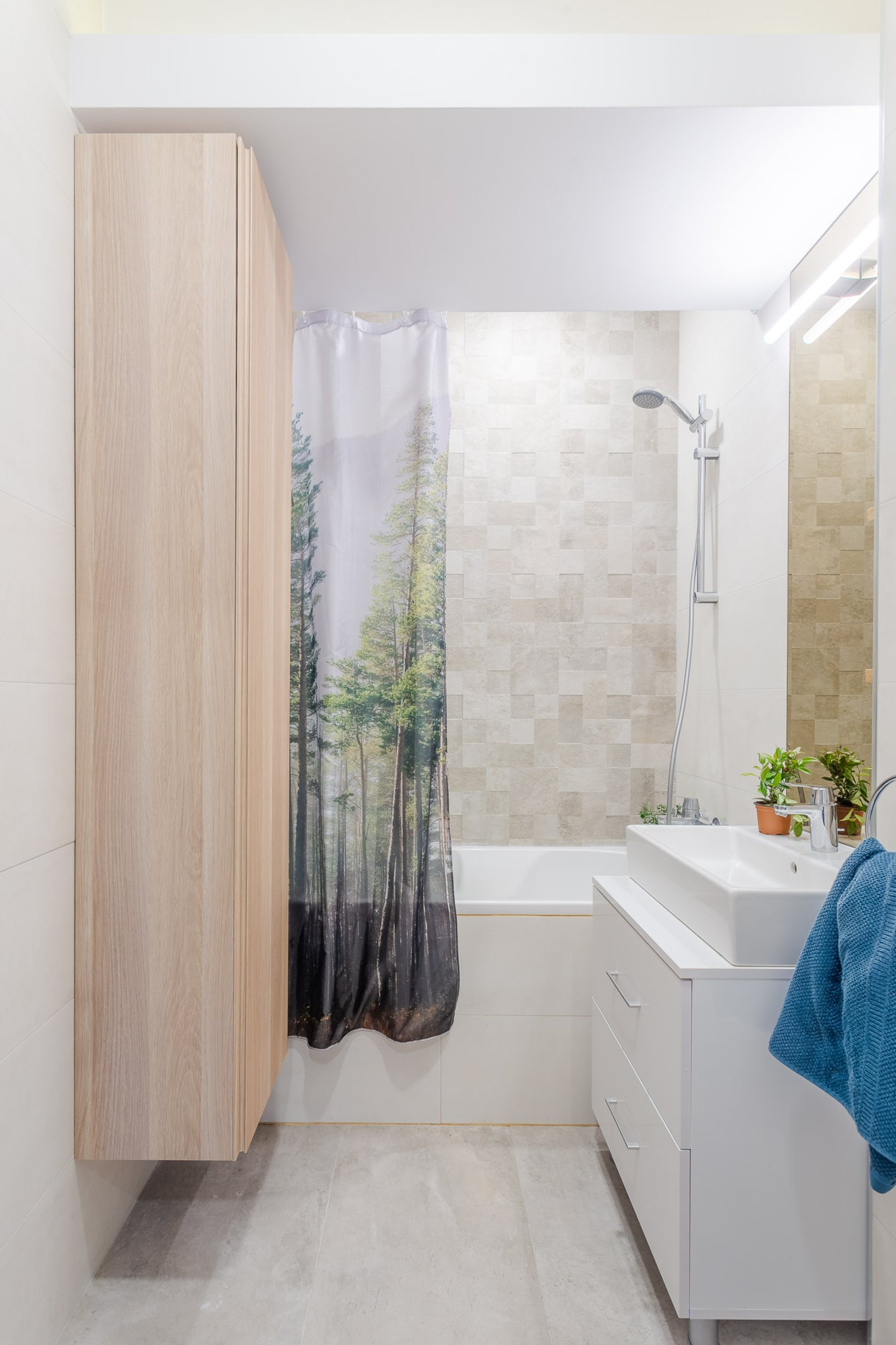 Amenajare apartament de burlac - baie minimalistă, mobilier alb, perdea de duș, dulap suspendat