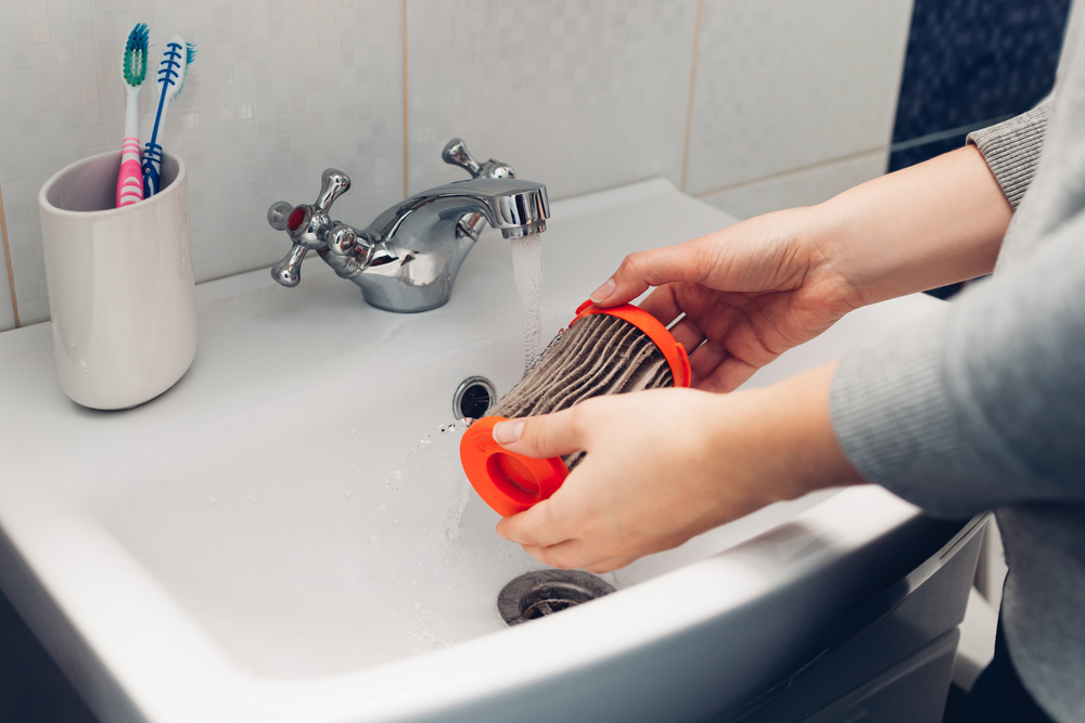 spălare filtru murdar aspirator la chiuveta de către femeie care face curățenie 