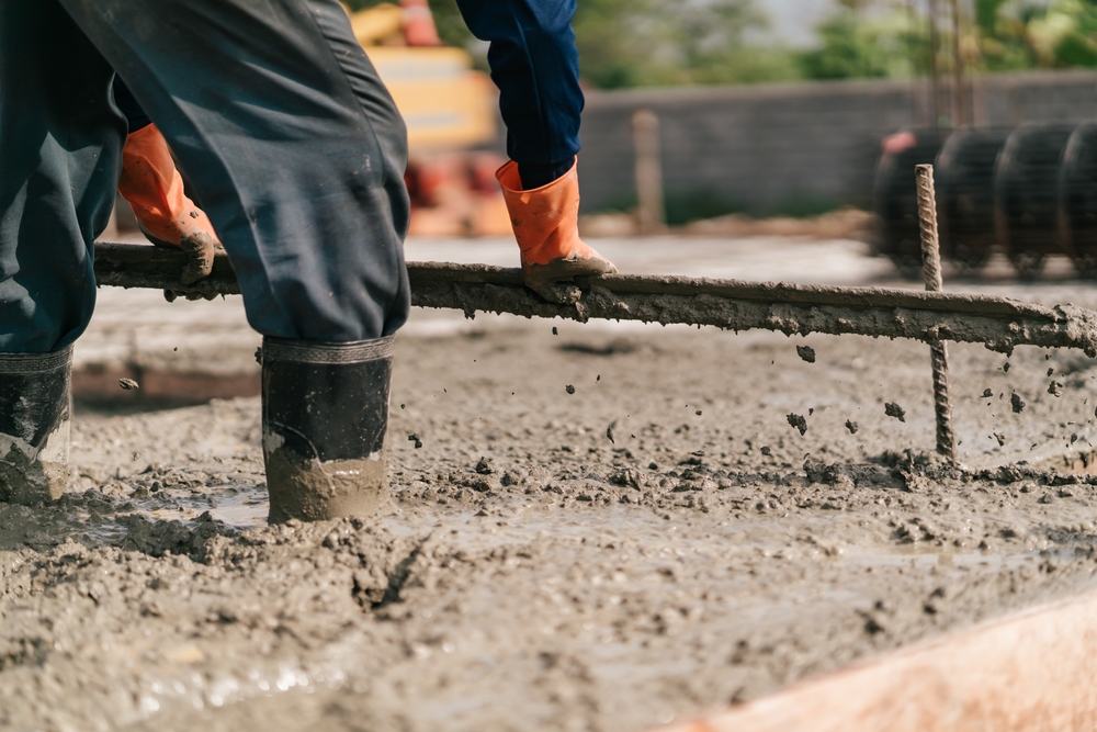 beton turnat sub forma de placa de către muncitor care sta chiar in beton 