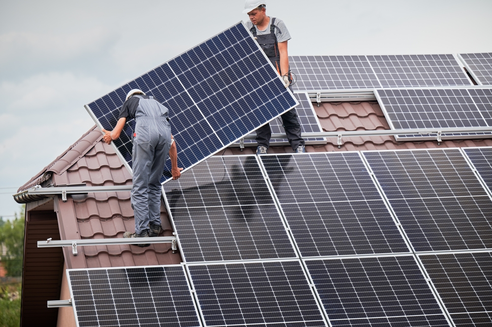 instalare panou fotovoltaic pe casa de către muncitori